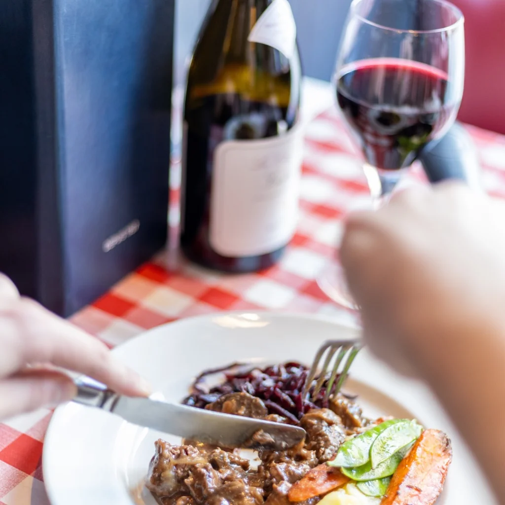 Someone Eating French Food at Chez Jules with a bottle of wine