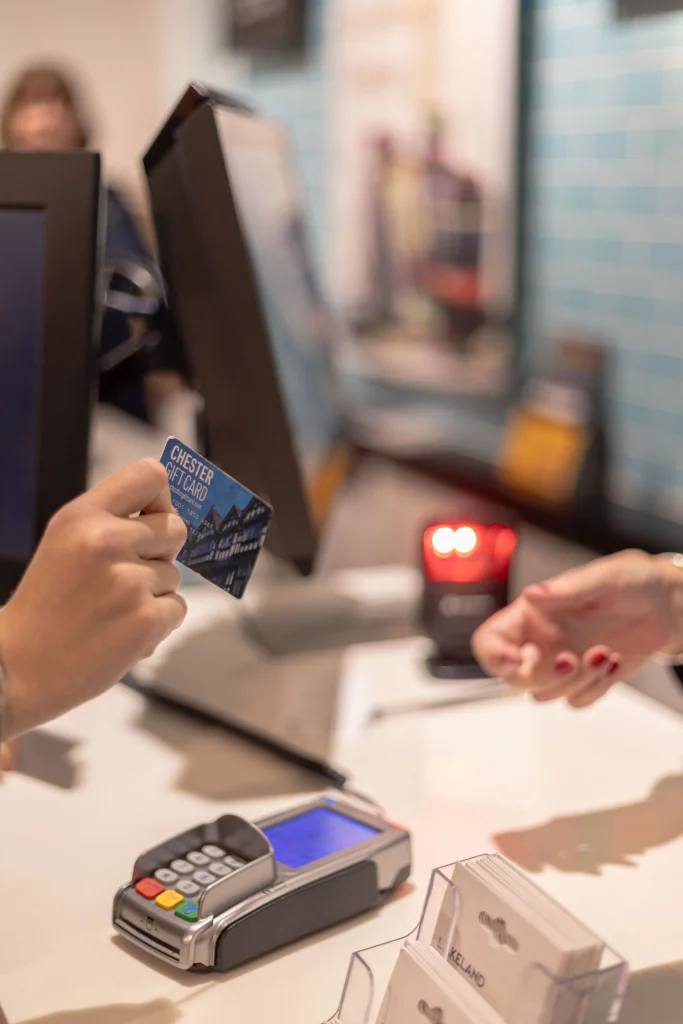 Close-up of a hand holding a Chester gift card paying in a store.