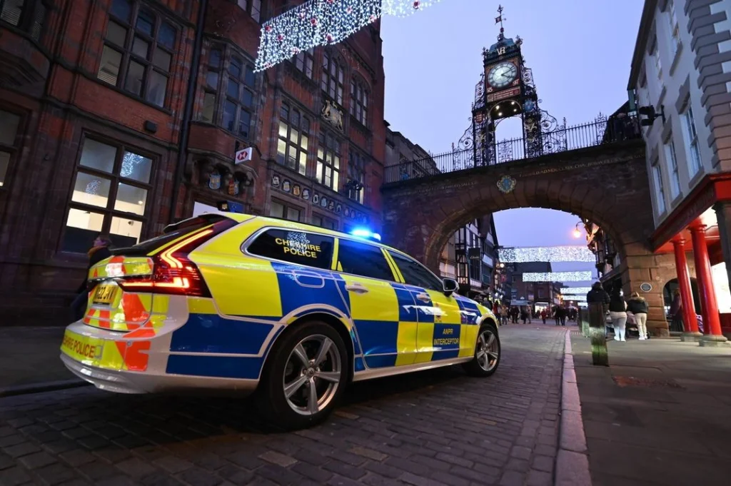 A police vehicle with flashing lights in front of Eastgate Clock at dusk.