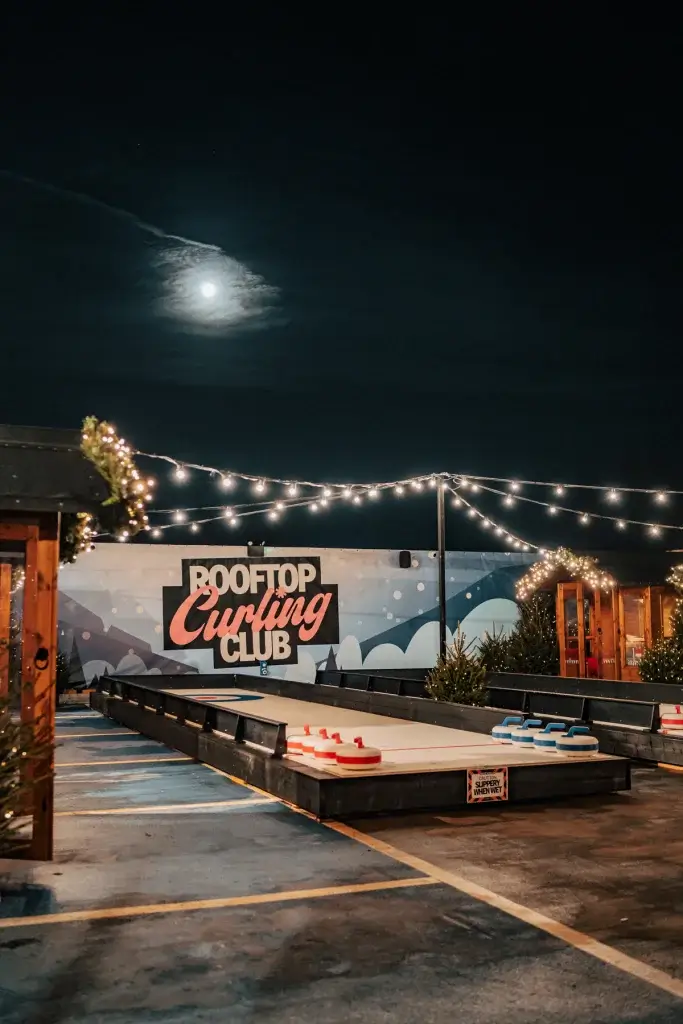 Curling game surrounded by twinkly lights with the moon in the background