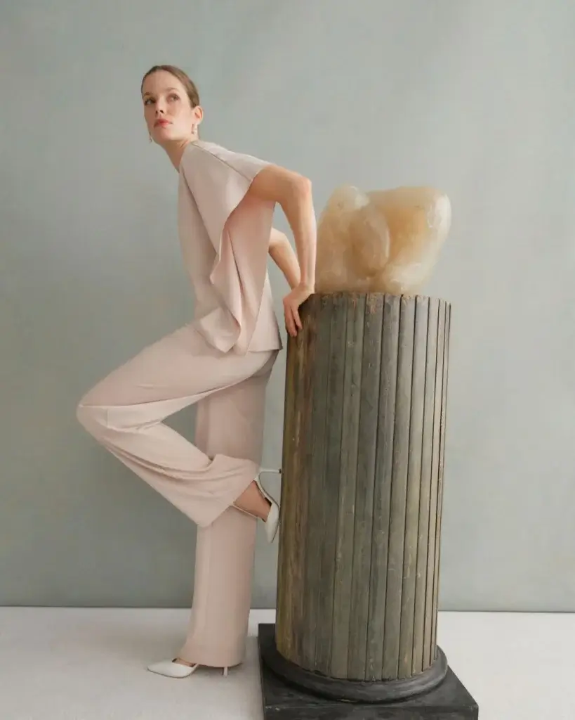 Female model wearing pink body suit standing next to a podium