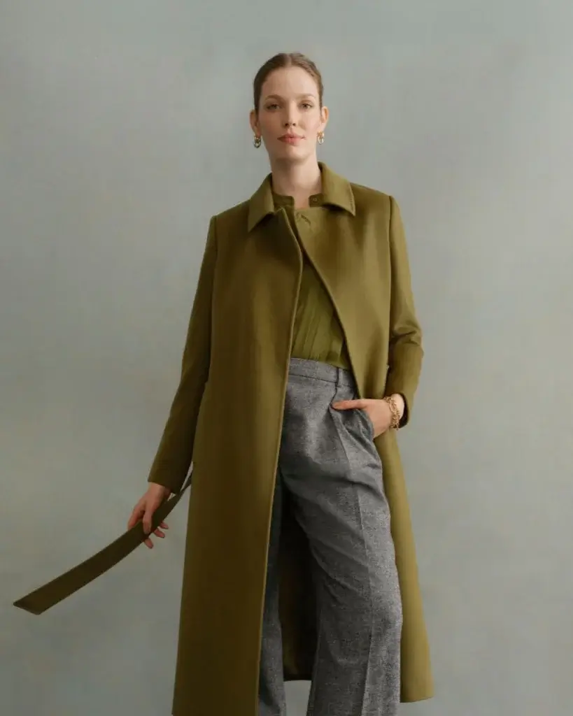 Female model wearing black trousers and green coat