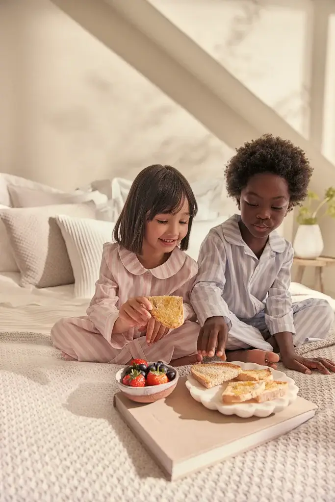 a boy and a girl eating fruit from a bowl