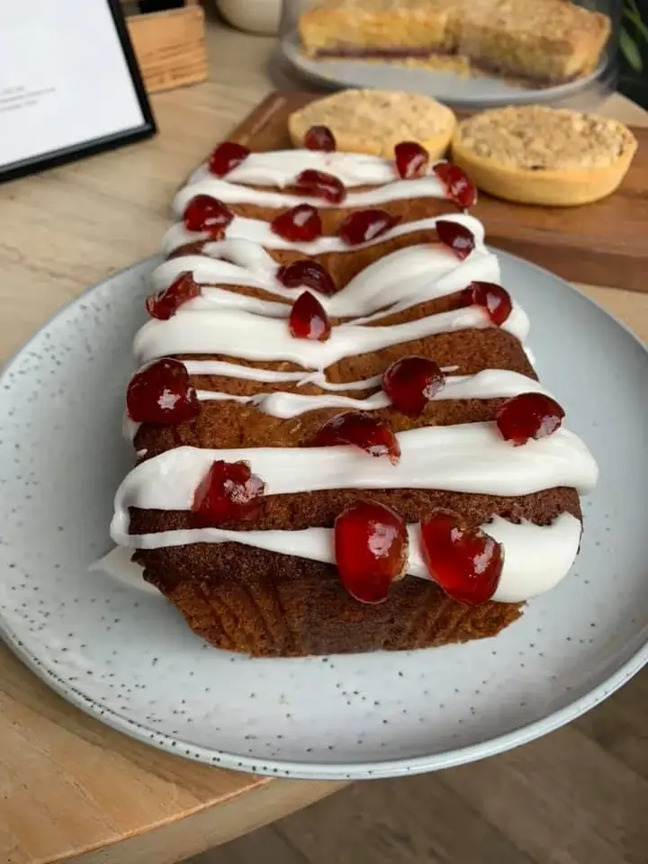 A Cake topped with icing and cherries