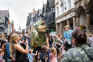 woman taking a photo of dinosaur on Eastgate street in chester