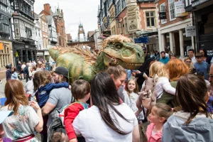 T rex walking through chester city centre through crowds of people