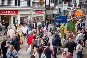 Stegosaurus walking through chester city centre through crowds of people