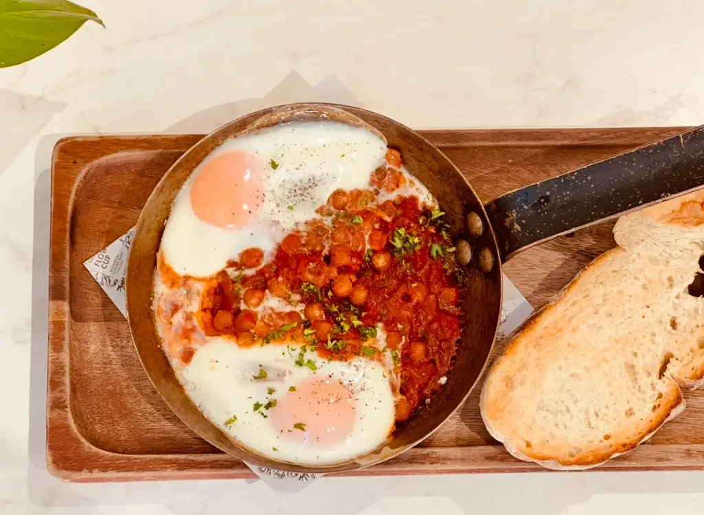 eggs shakshuka on a wooden board with crusty bread