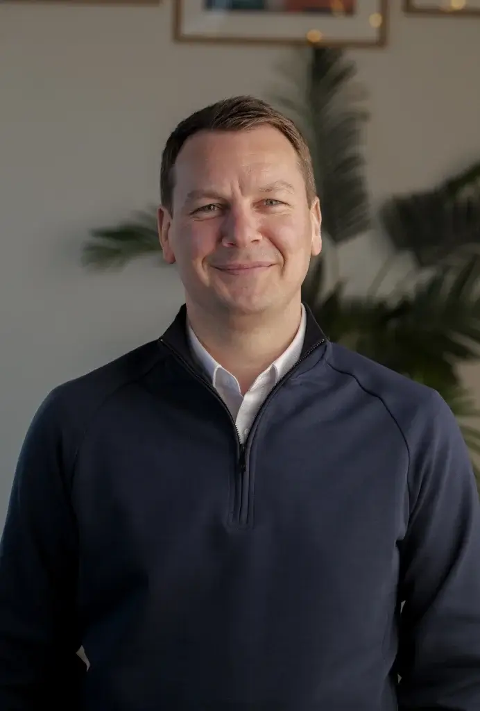 a man smiling to camera with a white shirt and navy jacket