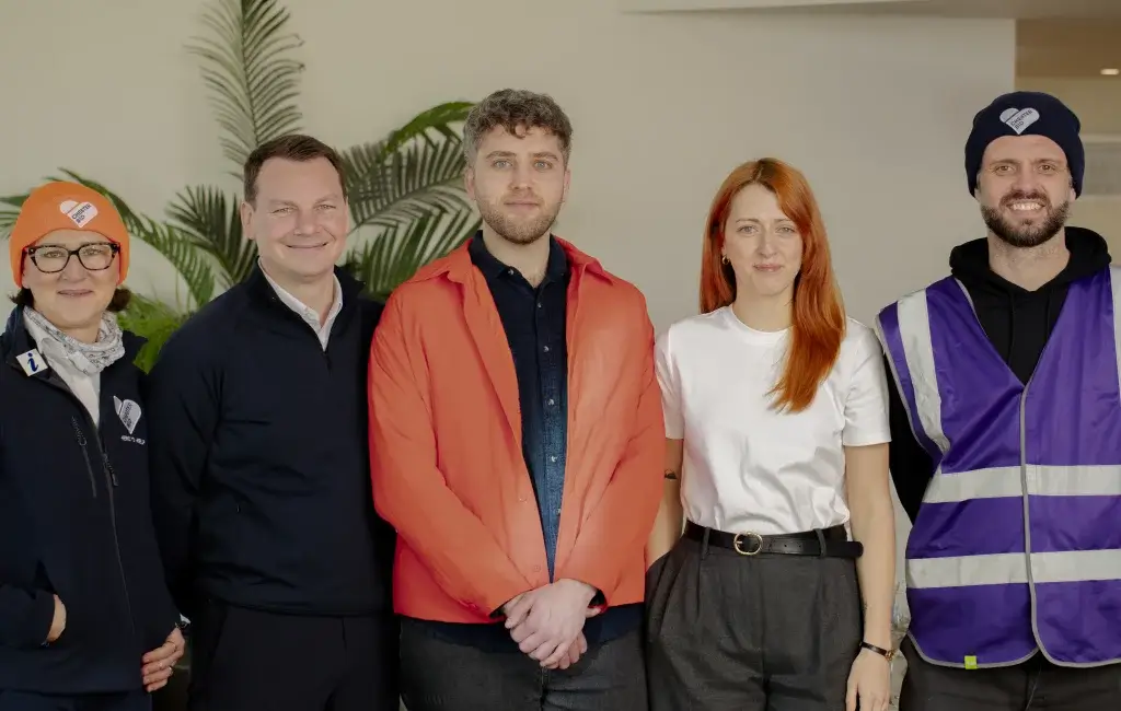 From left to right we have a woman wearing a orange hat and glasses, a man wearing a navy jacket, a man wearing a red jacket and black shirt, a woman with orange hair and a white top and lastly a man with a beard in a a purple high vis jacket and hat