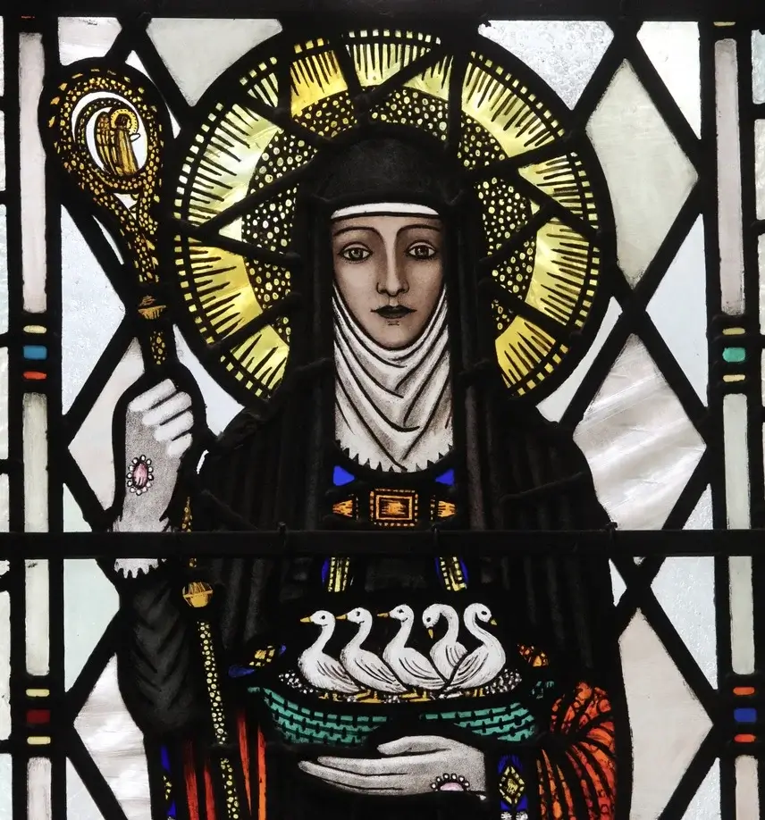 A stained glass window of Trena Cox. A woman holding 5 birds in her hand and a staff with a yellow glow behind her head