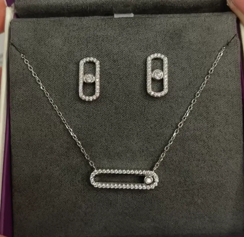 A sparkling silver jewelry set featuring a necklace and matching earrings, adorned with small, glimmering gemstones in an elegant design.